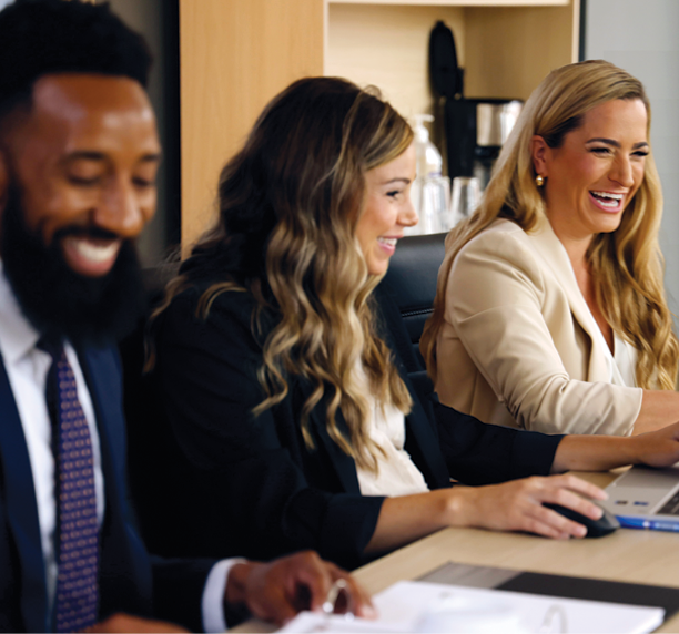 Image of attorneys smiling, sitting around conference table having a conversation.